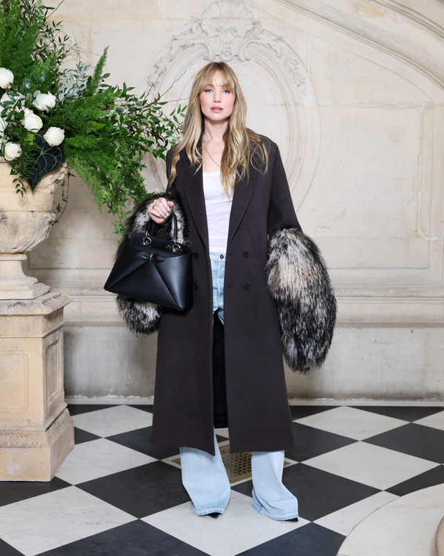 ディオールの2026年春夏オートクチュール コレクションでジェニファー・ローレンスは、袖口にファーのディテールを施した2026年フォール コレクションのウール&シルクのブラウンコートに、ホワイトコットンのトップス、ライトブルーデニムのブーツカットジーンズを合わせました。