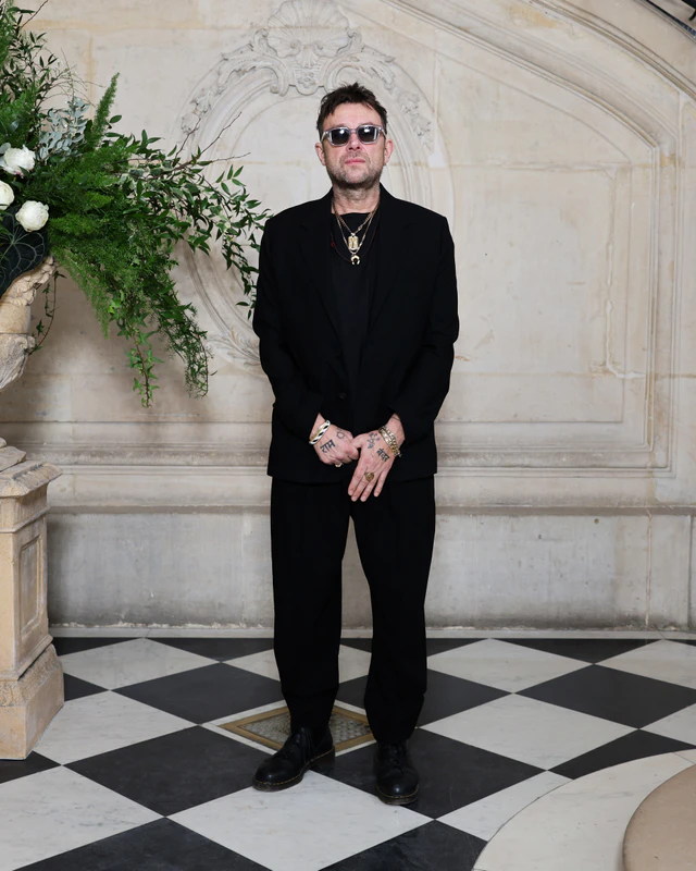 ディオールの2026年春夏オートクチュール コレクションでデーモン・アルバーンはブラックウールのノッチドラペルスーツに、ブラックのコットンTシャツ、ブラックレザーのダービーシューズを合わせました。